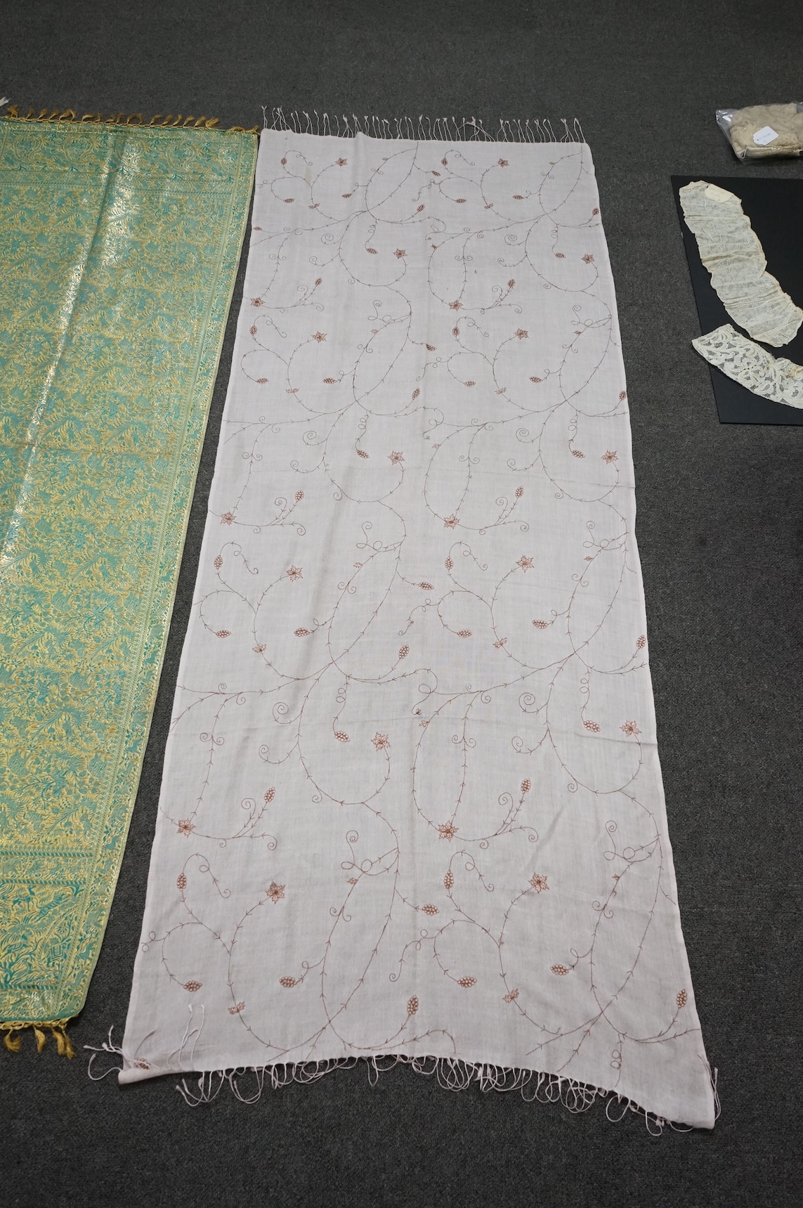 An Indian green and gold silk hand woven brocade stole, a cream pashmina embroidered stole and a similar finely woven and embroidered lilac stole (3). Brocade stole 38cm x 180cm., Condition - light stain to finely woven